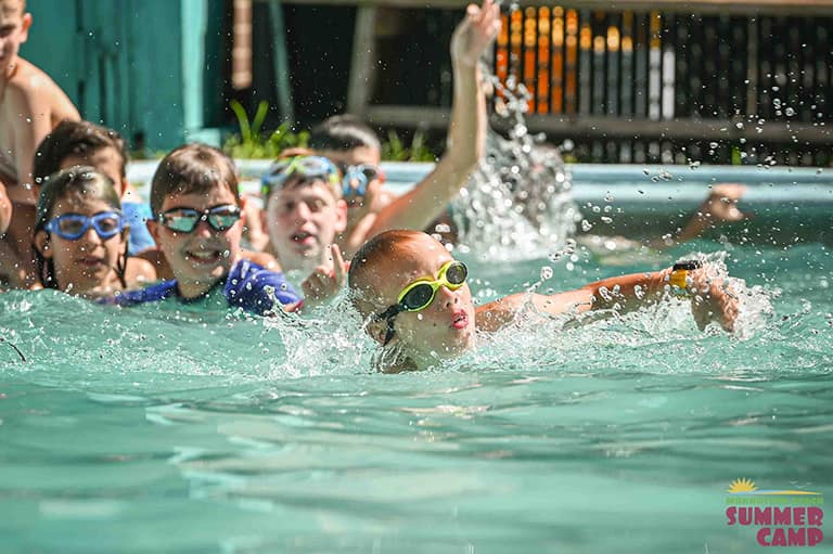 children swimming in a pool of a summer camp